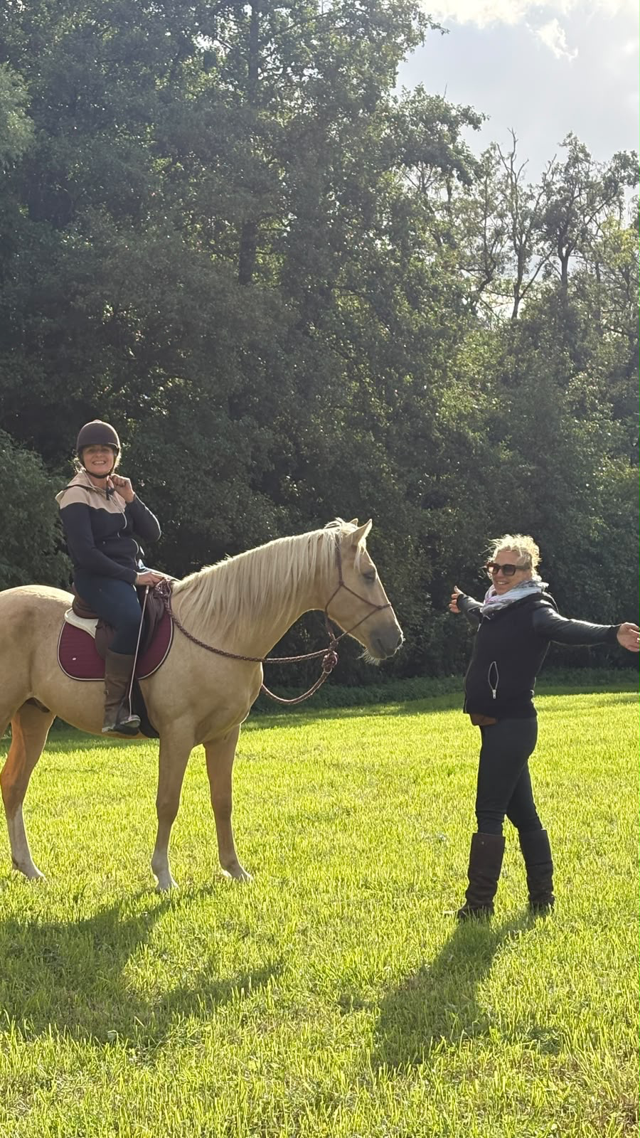 Une cavalière sur un cheval accompagné d’une enseignante dans un pré